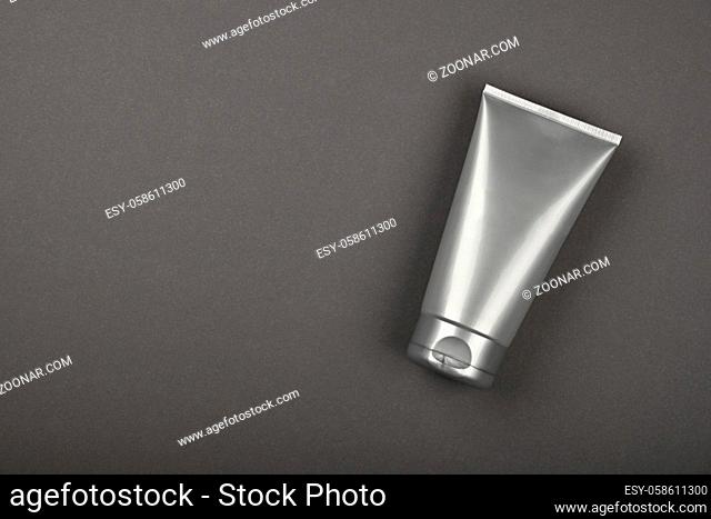 Close up men grooming product, personal care cream, lotion or gel in silver grey tube, elevated top view, directly above