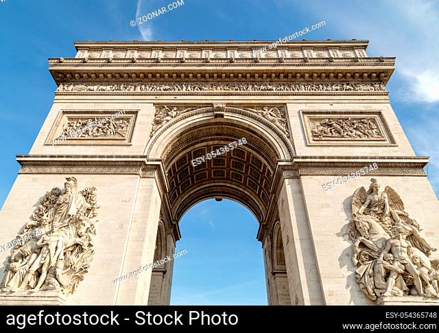 Arc de Triomphe in Paris under sky with clouds. One of symbols of France and one of the most popular tourist places in the world
