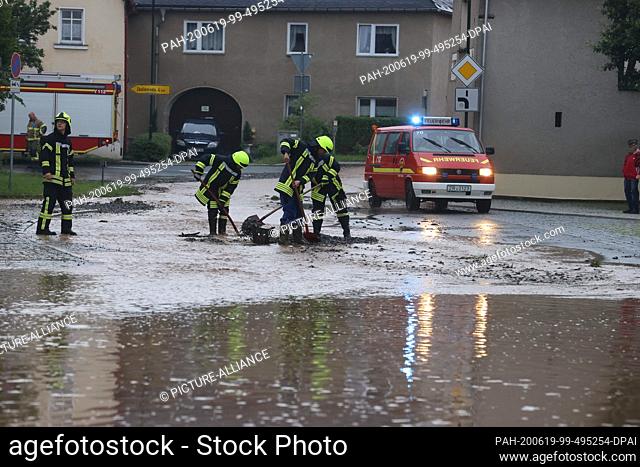 19 June 2020, Thuringia, Zeulenroda-Triebes: Firefighters try to clear a drain of garbage on a flooded square in the middle of the small town