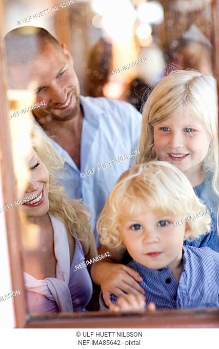 Family standing beside window, smiling