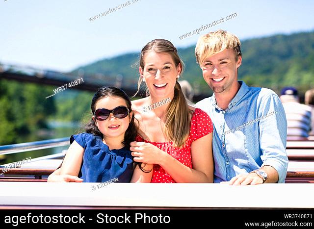 Happy family sitting happily on boat on river cruise in summer