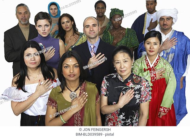 Multi-ethnic people in traditional dress holding hand on heart