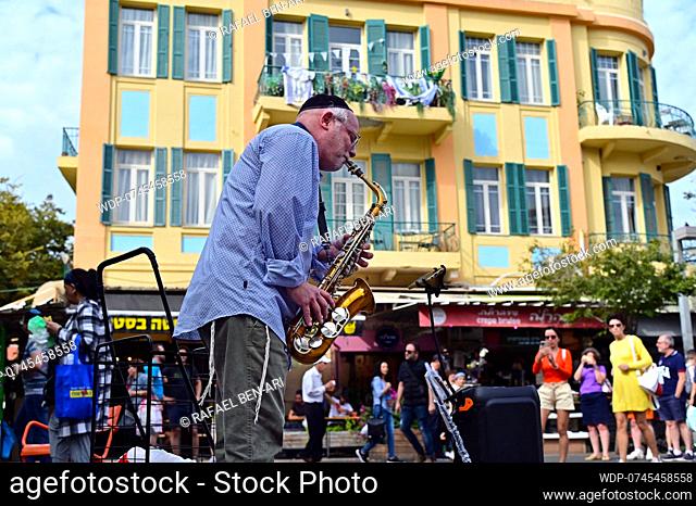 TEL AVIV YAFO - NOV 22 2022:Jewish saxophonist play music in street .The music of Israel is a combination of Jewish and non-Jewish music traditions that have...