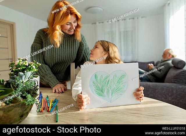 Girl with mother at table showing a drawing