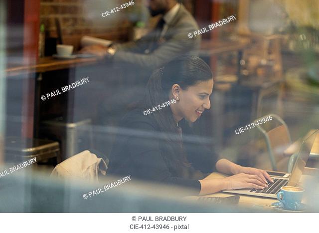 Smiling businesswoman working at laptop in cafe