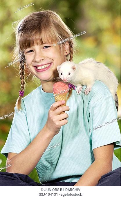 girl feeding white domestic polecat with ice-cream / Mustela putorius f  furo