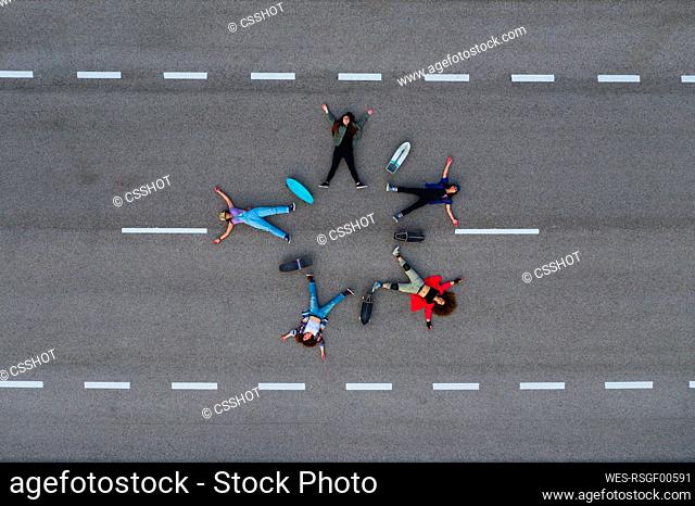 Female friends with skateboards lying down on road