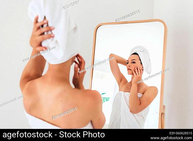 Woman stands in front of a mirror after a bath