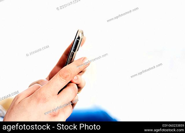 the hands of a young caucasian brunette woman while holding a smartphone typing on the touch screen. Technology and mobile connection