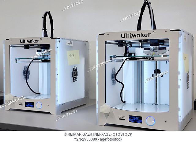 Two 3D three dimensional printers extruding Polylactic acid PLA polymer to print a plastic object