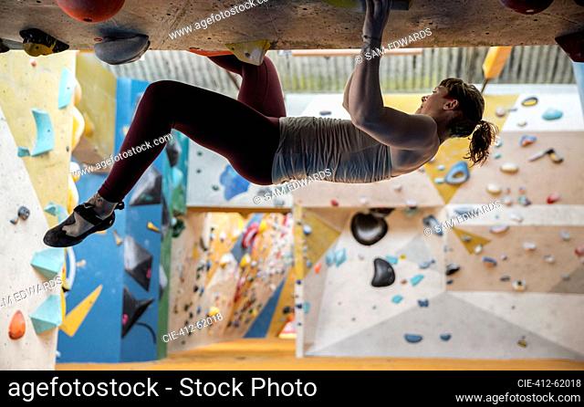 Young woman rock climbing upside-down