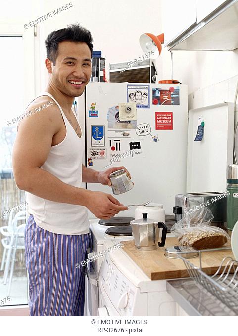 Smiling man in kitchen making coffee