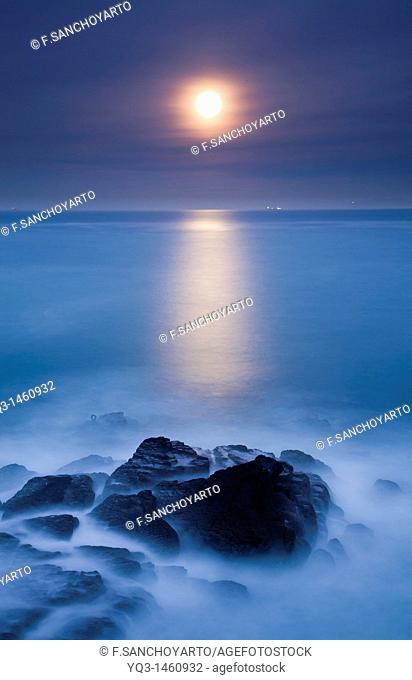 Night view of the moon rising over the sea