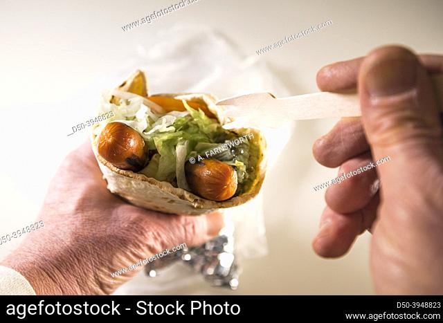 A classic Swedish tunnbrodsrulle, a wrap with mashed potaoes, hotdogs, salad and a condiment like pickled cucumbers