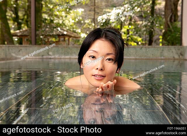 Portrait beautiful young woman soaking in pool at Onsen
