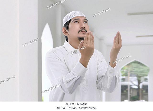 Religious asian muslim man with white cap praying on the mosque