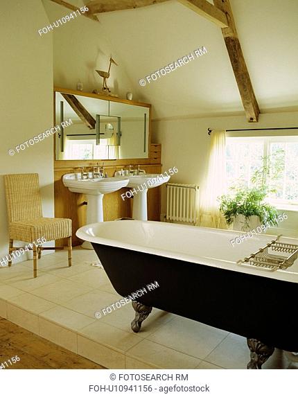 Roll-top bath in traditional beamed bathroom under the eaves of an attic conversion