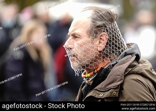 18 November 2020, Berlin: A participant of a demonstration against the corona restrictions of the German government wears a net in front of his mouth and nose...