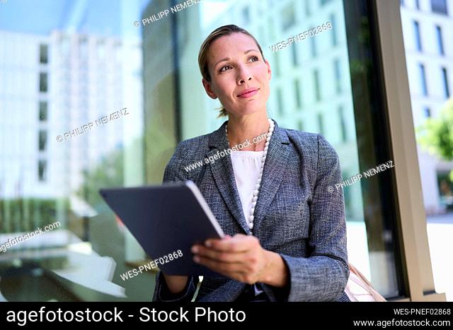 Thoughtful businesswoman holding tablet PC
