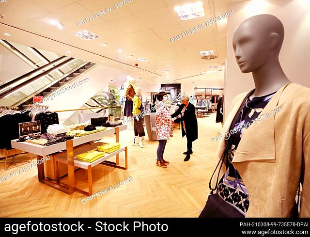08 March 2021, North Rhine-Westphalia, Essen: An employee of the Sinn fashion chain serves one of the first customers in the women's department after the...