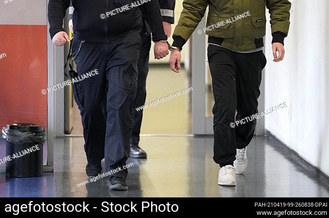 19 April 2021, Hamburg: A defendant (r) is brought in handcuffs to the courtroom of the St. Georg District Court for the trial of two 26-year-olds for joint...