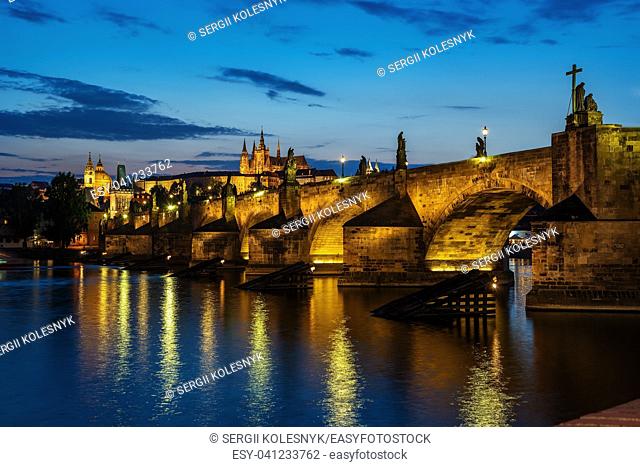 Illuminated Charles Bridge on river Vltava in Prague at sunset