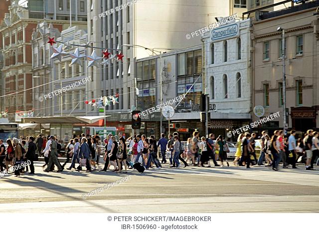 Pedestrians crossing a traffic light on Flinders Street in the heart of Melbourne, Victoria, Australia