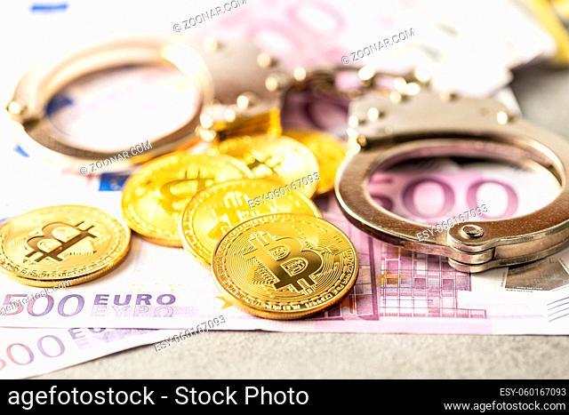 Euro banknotes, bitcoins and handcuffs. Coins of a cryptocurrency