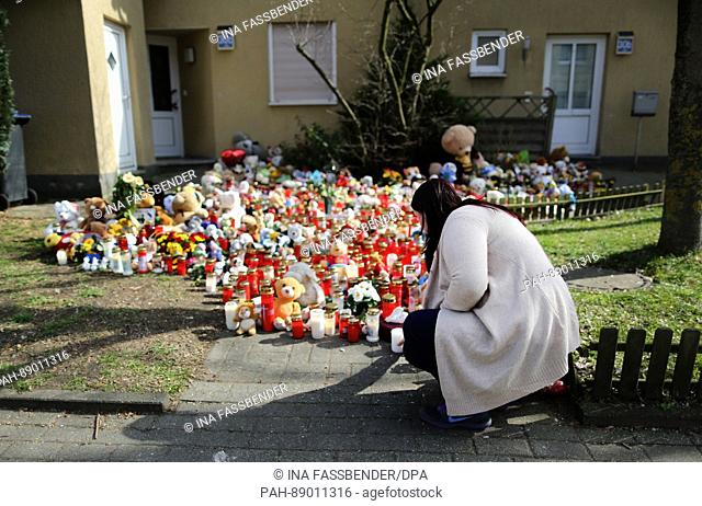 A woman lays down a candle in a front yard of a house in Herne, Germany, 14 March 2017. After the double murder the local church will be holding an ecumenical...