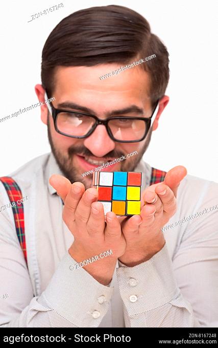 Concept happy, nerd. Confident handsome boy nerd holding a puzzle cube and felling proud isolated on white background