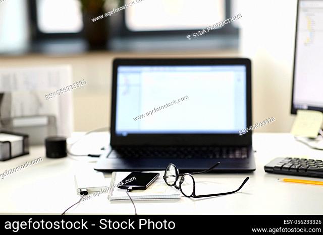 laptop, smartphone and notebook on table at office