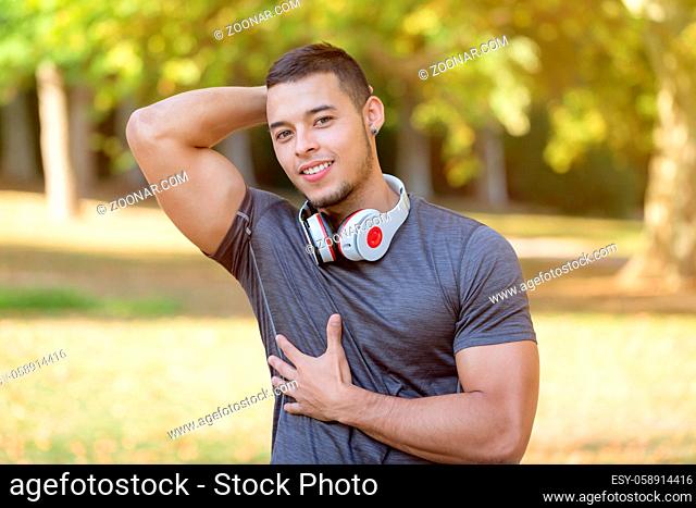 Flexing muscles posing runner young latin man running jogging sports training fitness workout copyspace copy space outdoor