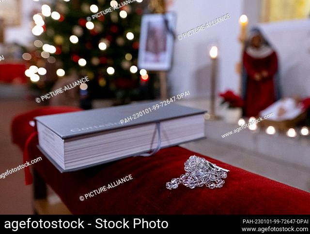 01 January 2023, Bavaria, Marktl: A rosary and hymnal lie on a bench in St. Oswald Church during a service for Pope Emeritus Benedict XVI