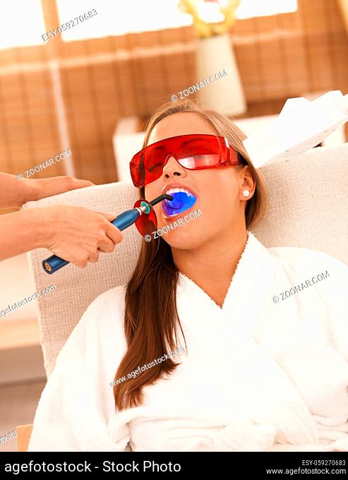 Young woman getting laser tooth whitening treatment at spa