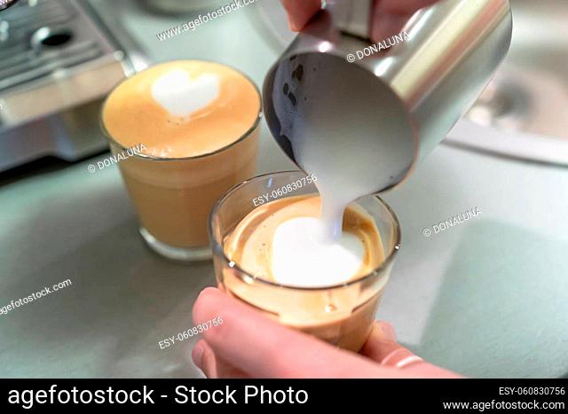 A man cooks cappuccino at home, pours milk from the pitcher into a glass