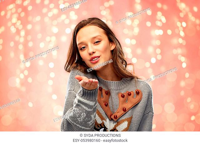 woman in ugly christmas sweater sending air kiss