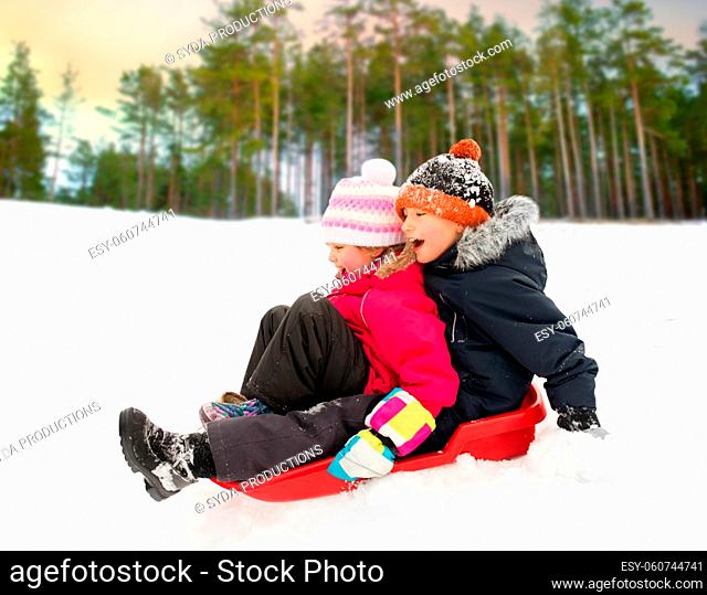 little kids sliding on sled down hill in winter