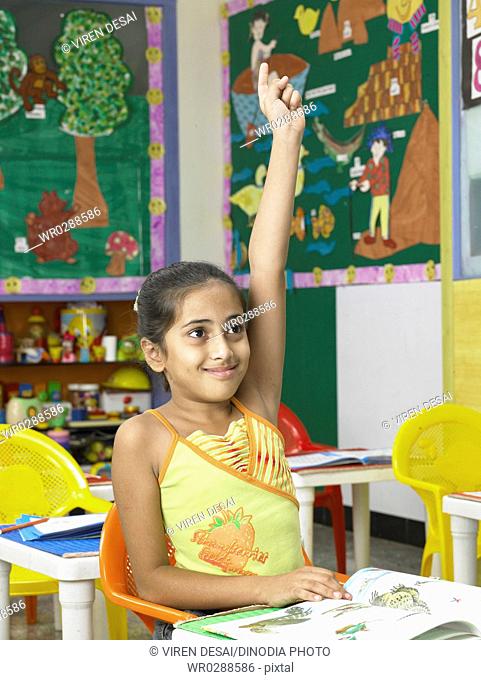 South Asian Indian girl raising hand for replaying answer in nursery school MR