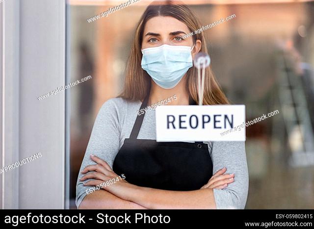 woman in mask with reopen banner on door glass