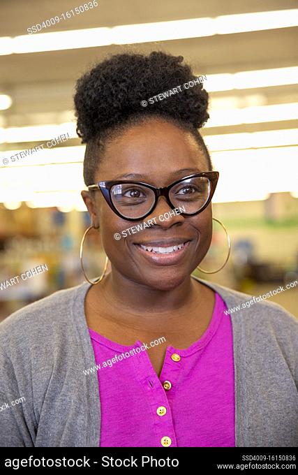 Portrait of smiling woman wearing retro glasses and large hoop ear rings, looking off camera smiling