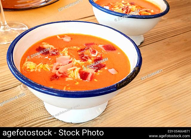 Salmorejo, Spanish cold tomato soup in a rustic bowl on a wooden table