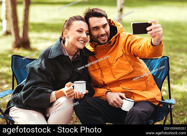 couple drinking tea and taking selfie at tent camp