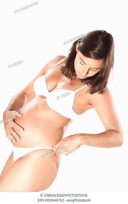 caucasian pregnant woman examining her hips legs isolated studio on white background