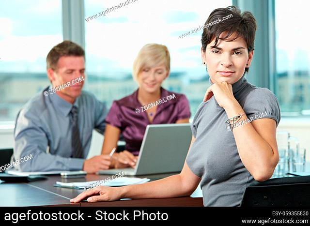 Smiling businesswoman on business meeting at office with team in background