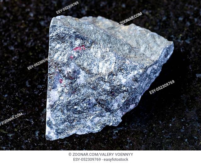 macro shooting of natural mineral rock specimen - raw antimonite stone on dark granite background from Chauvay district of Kyrgyzstan