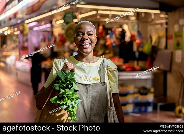 Portrait of happy woman buying groceries in a market hall