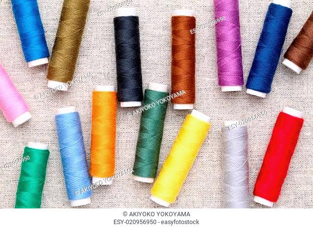 spool of sewing threads on burlap background