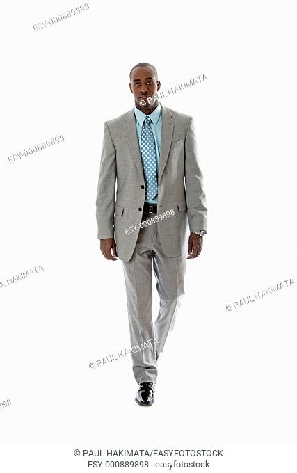 Handsome African American man in gray suit walking, isolated