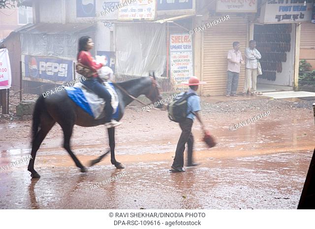 Woman riding horse on road in monsoon season ; Matheran ; Maharashtra ; India