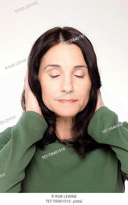 Studio portrait of mature woman covering ears